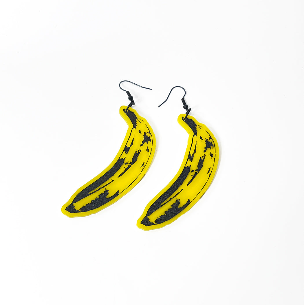 Yellow acrylic pop art banana earrings on white background 